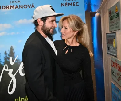Muž a žena stojí blízko u sebe před filmovým plakátem, kterému dominuje modrá barva