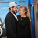Muž a žena stojí blízko u sebe před filmovým plakátem, kterému dominuje modrá barva