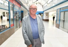 Muž ve světlém obleku stojí ve vestibulu a nechává se fotit