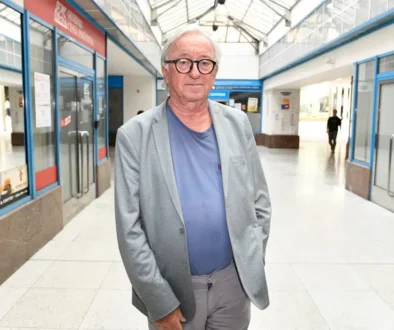 Muž ve světlém obleku stojí ve vestibulu a nechává se fotit