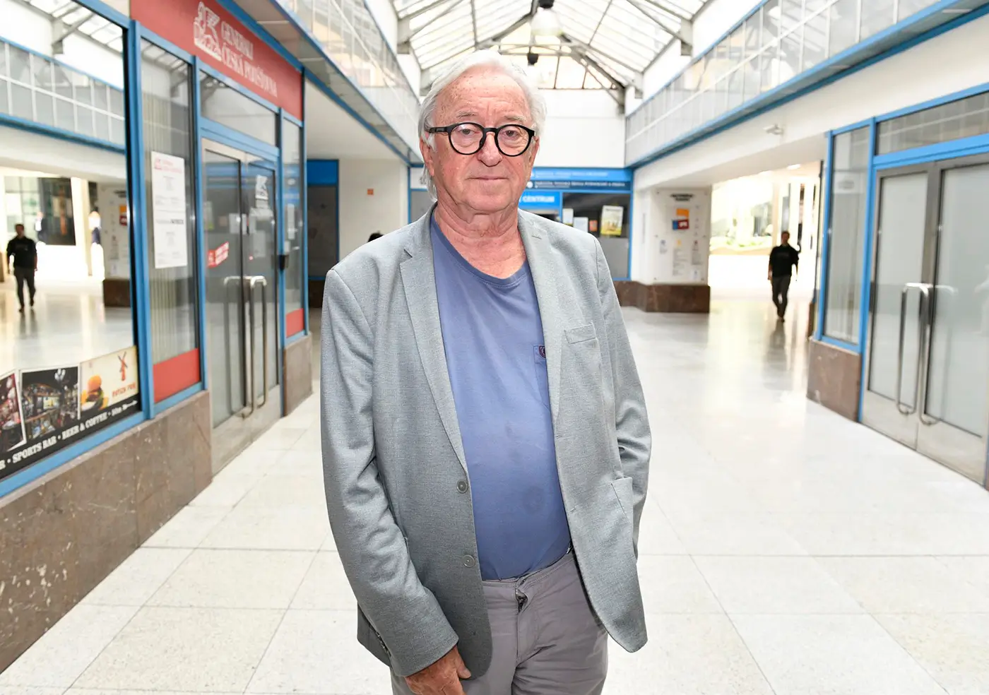 Muž ve světlém obleku stojí ve vestibulu a nechává se fotit