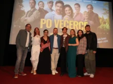 Skupina lidí stoji na podiu pod filmovým plátnem
