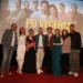Skupina lidí stoji na podiu pod filmovým plátnem
