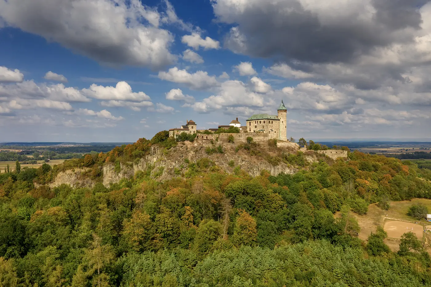 shutterstock_1921923155 - VIPshow Sluncem ozářená Kunětická hora na východě Čech s bujnou zelení okolo a s nebem s mraky