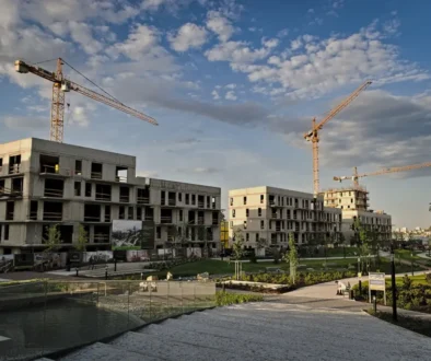 Fotografie výstavby bytového komplexu v pozadí s jeřáby