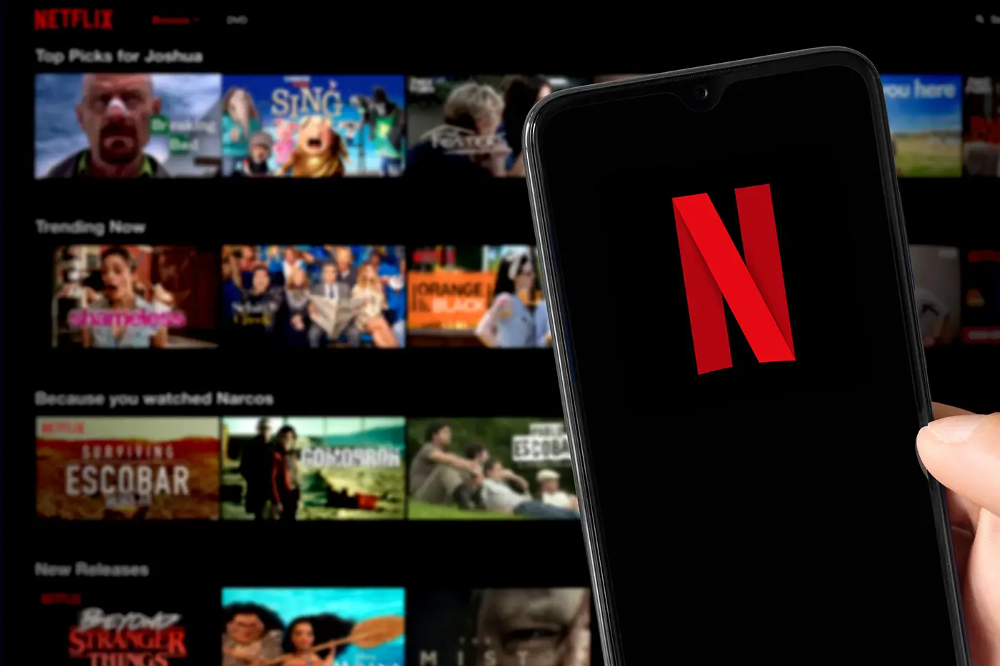 shutterstock_2567951911 - VIPshow Mobilní telefon s logem Netflix na pozadí s obrazovkou, na které jsou okýnka s jednotlivými pořady