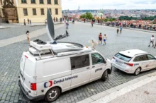 Dodávka České televize zaparkovaná na dlážděném Hradčanském náměstí