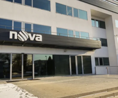 Moderní kancelářská budova. Na ní je v černé liště nápis NOVA