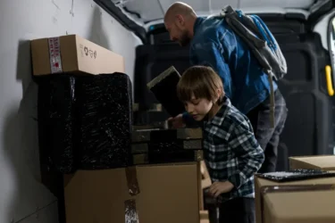 Dospělý muž a malý chlapec se nacházejí v dodávce a prohledávají krabice