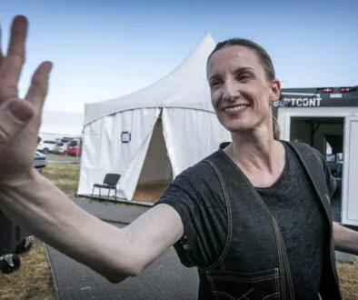 Smějící se žena v černém tričku u bílých stanů