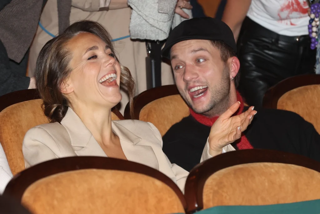 Smějící se pár na sedadlech v kině.