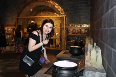 Žena s černými vlasy a v černých šatech se sklání nad stolem