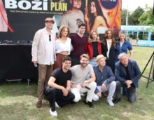 Skupina lidí pózuje před plakátem s nápisem Boží plán