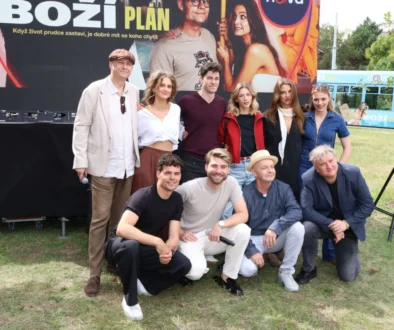 Skupina lidí pózuje před plakátem s nápisem Boží plán