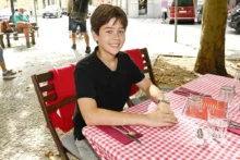 Malý chlapec sedí na židli u stolu, který je pokrytý kostkovaným ubrusem