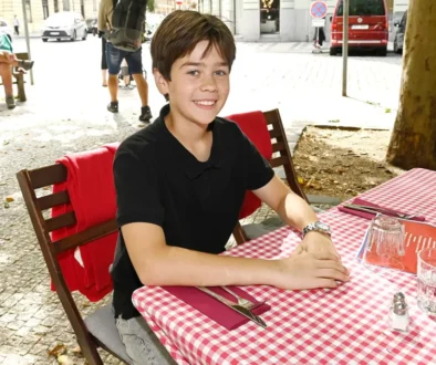 Malý chlapec sedí na židli u stolu, který je pokrytý kostkovaným ubrusem
