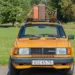Staré žluté auto má na střeše přivázané kufry