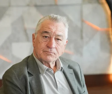 Starší muž s šedivými vlasy, ve světlé košili a v tmavším saku, je zahleděný do strany