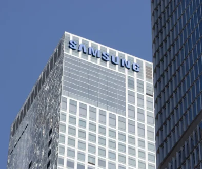 Vysoká moderní budova, nad ní modré nebe, na budově je nápis Samsung