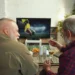 Dva starší muži sedí před televizí a sledují fotbal