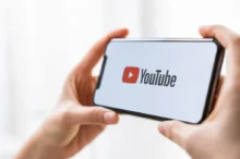 Člověk v ruce drží chytrý telefon s logem streamovací platformy YouTube