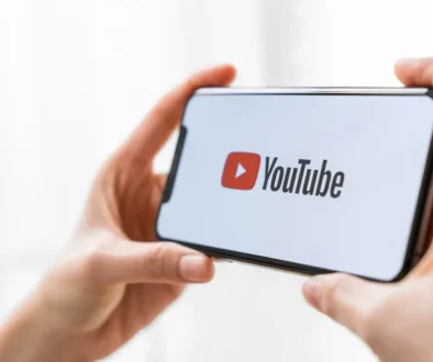 Člověk v ruce drží chytrý telefon s logem streamovací platformy YouTube