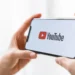 Člověk v ruce drží chytrý telefon s logem streamovací platformy YouTube