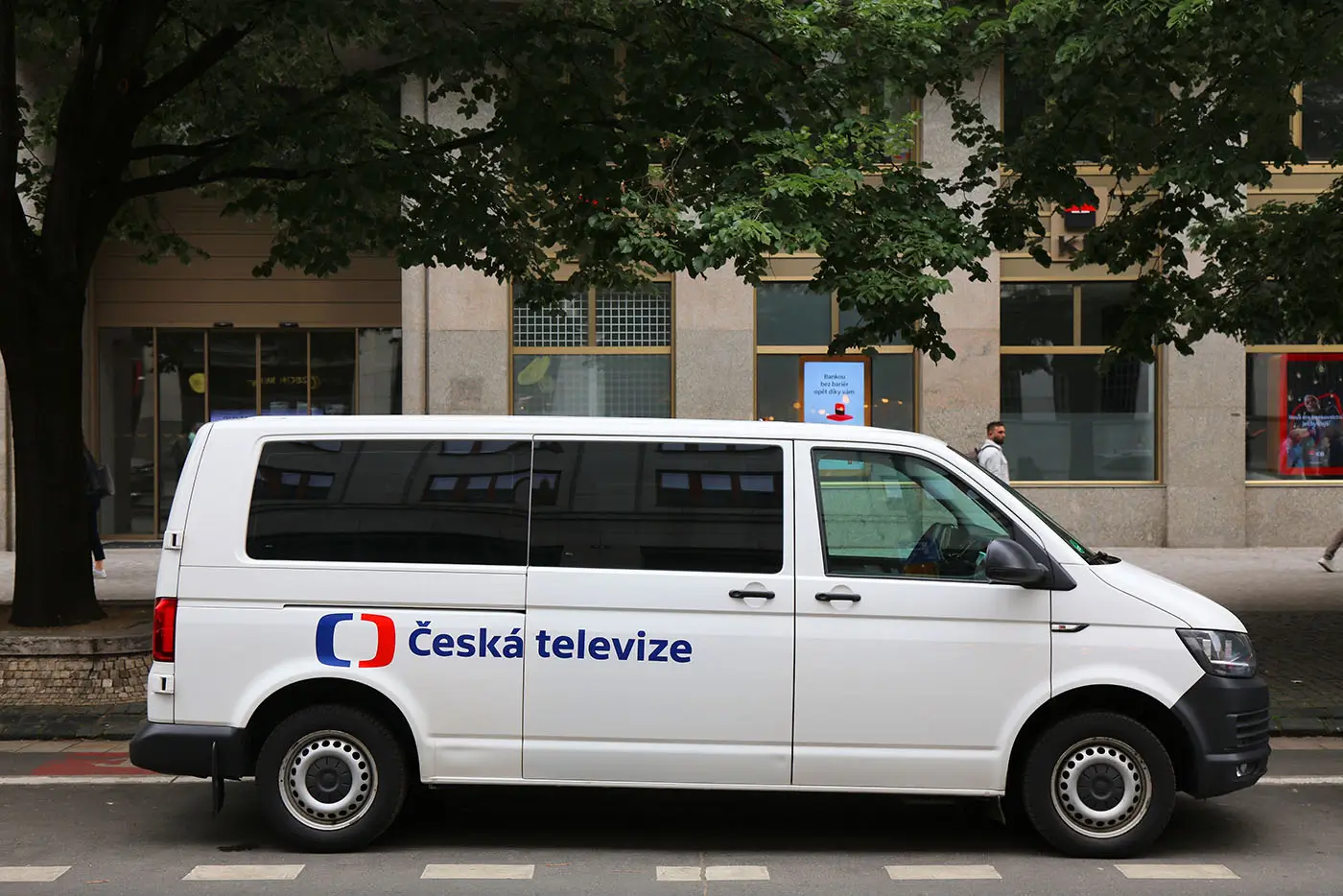 Bílá dodávka veřejnoprávní televize stojí venku na ulici