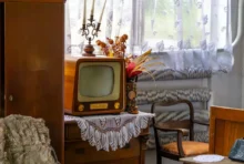 Na stole s háčkovanou dečkou stojí malá stará televize