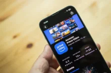 Člověk drží v ruce mobilní telefon a na něm je zobrazená streamovací platforma