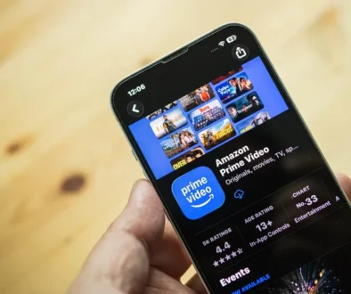 Člověk drží v ruce mobilní telefon a na něm je zobrazená streamovací platforma