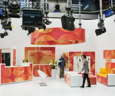 Studio laděné do oranžové a bílé barvy, ve kterém stojí muž a žena