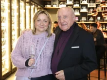 Muž a žena se skleničkou v ruce stojí vedle sebe a usmívají se do kamery