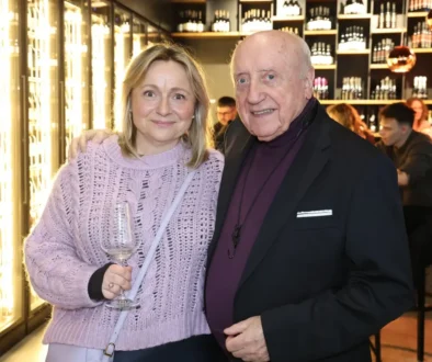 Muž a žena se skleničkou v ruce stojí vedle sebe a usmívají se do kamery