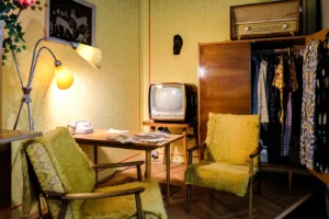 Stará televize se starým křeslem, s retro lampičkou, stolkem a poličkami