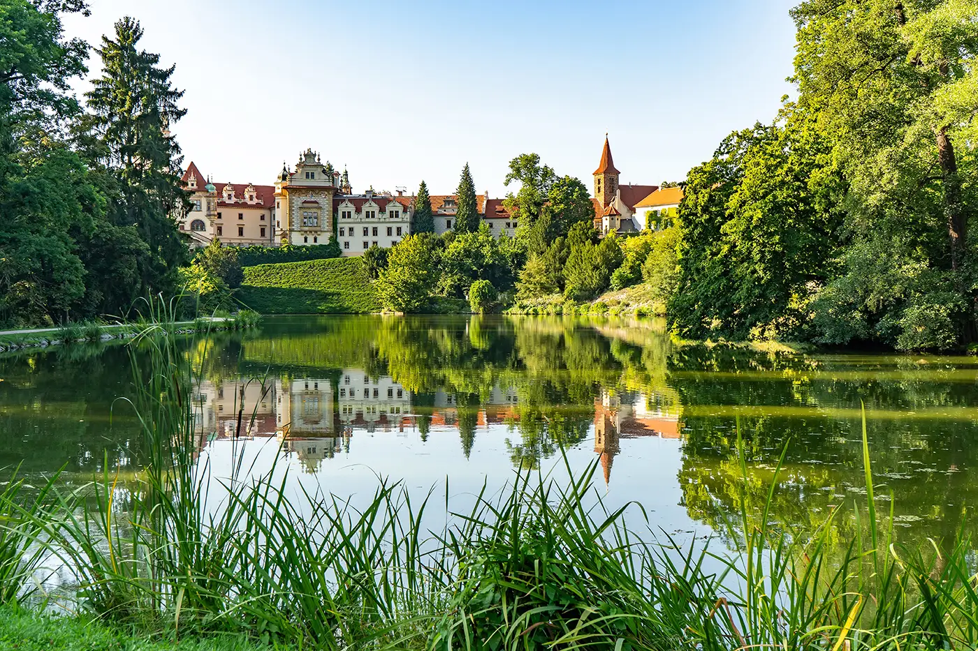 shutterstock_2430242847 - VIPshow Zámek v obklopení zeleně a před ním je jezero
