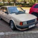 Na ulici stojí staré auto ve světlé barvě z osmdesátých let