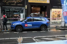 Na ulici stojí modré auto s logem televizní stanice