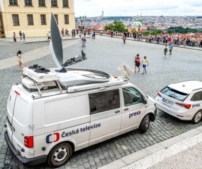 Na ulici na veřejném prostranství stojí dodávka a osobní auto veřejnoprávní televize