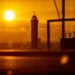 Silhouetted tower against a bright orange sunset with blurred foreground frames in an urban skyline