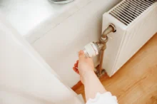 Osoba točí termostatem na radiátoru