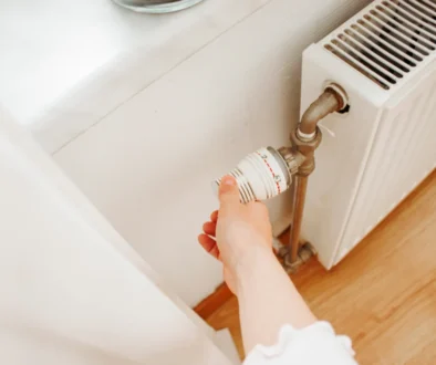 Osoba točí termostatem na radiátoru