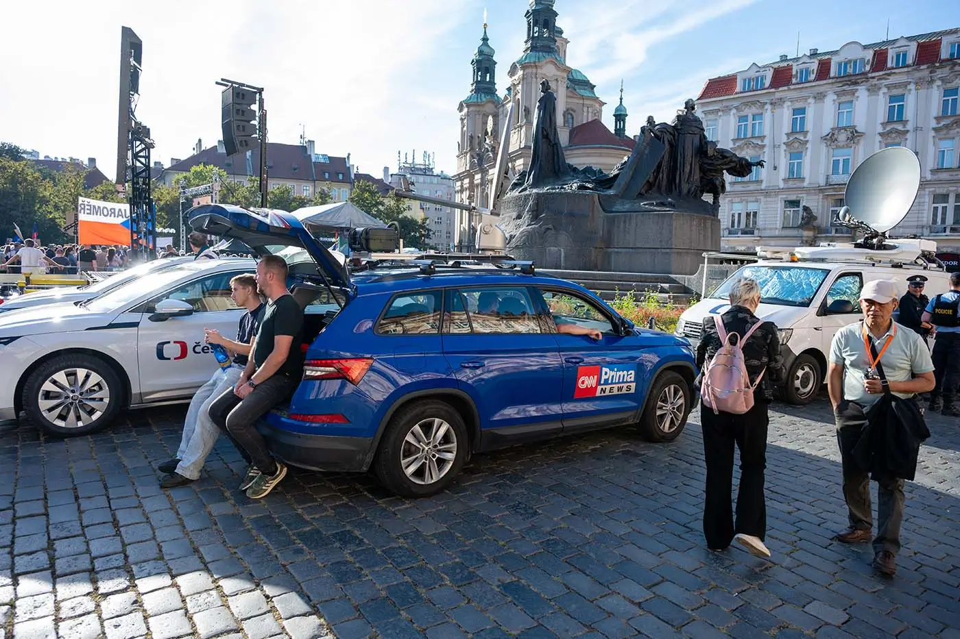 shutterstock_2852033625 - VIPshow Na Staroměstském náměstí v Praze stojí tři auta, dvě bílá a jedno modré a okolo nich je několik lidí